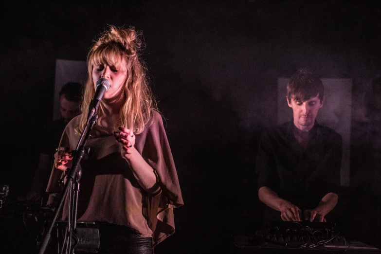 two people singing into microphones in front of a keyboard