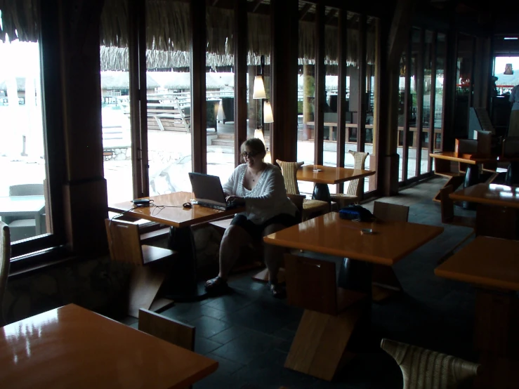 a lady sitting at her laptop outside of an asian restaurant