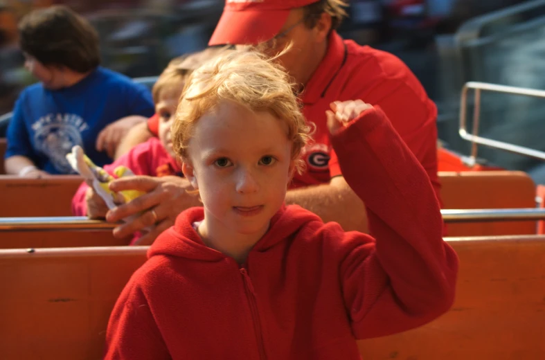 a child is wearing a red sweatshirt and has her hair tied in half