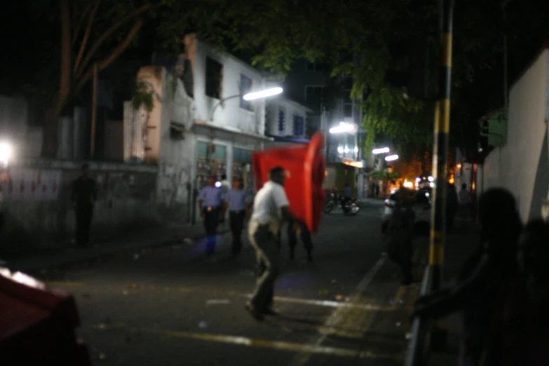 people walking in the dark on a sidewalk at night