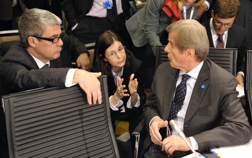 several people seated in chairs and one man is gesturing