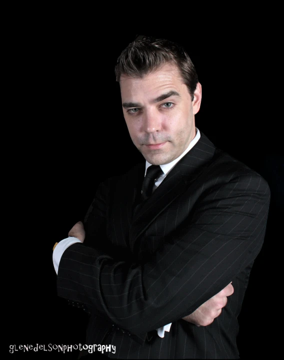 a man in a black suit with his arms folded