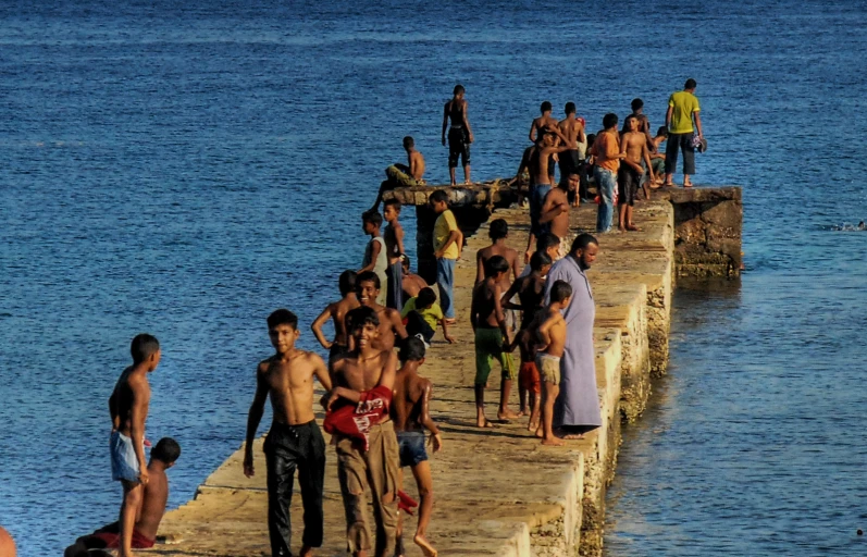 a number of people standing on some rocks next to water