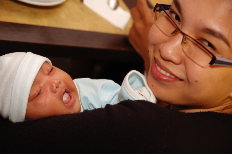 a person in glasses holding a baby smiling