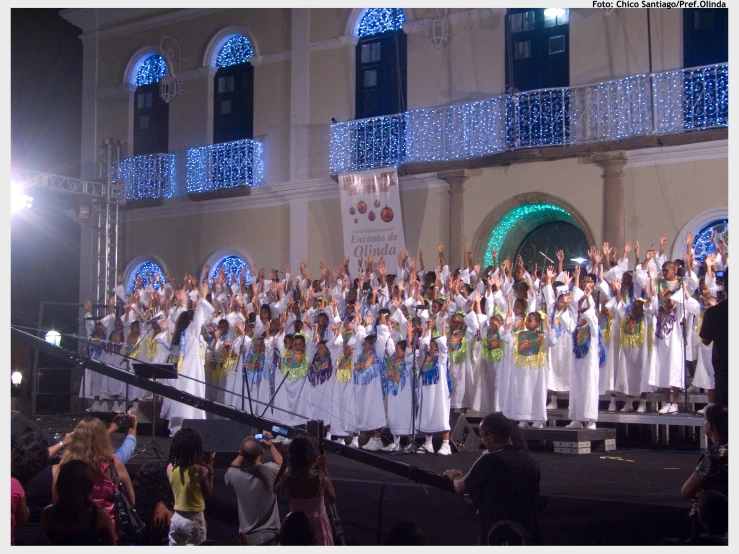 a group of women dressed in white dresses standing on top of stage