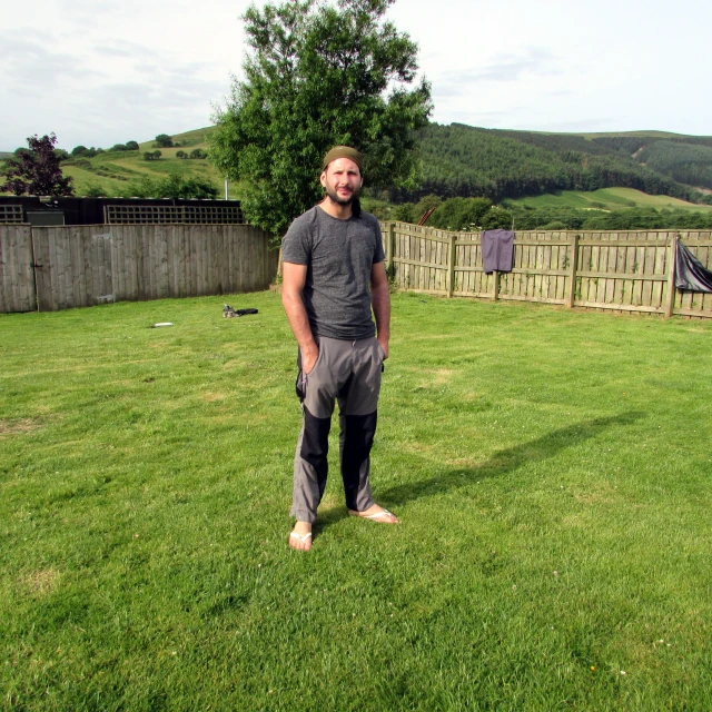 a man poses for the camera while in front of a field