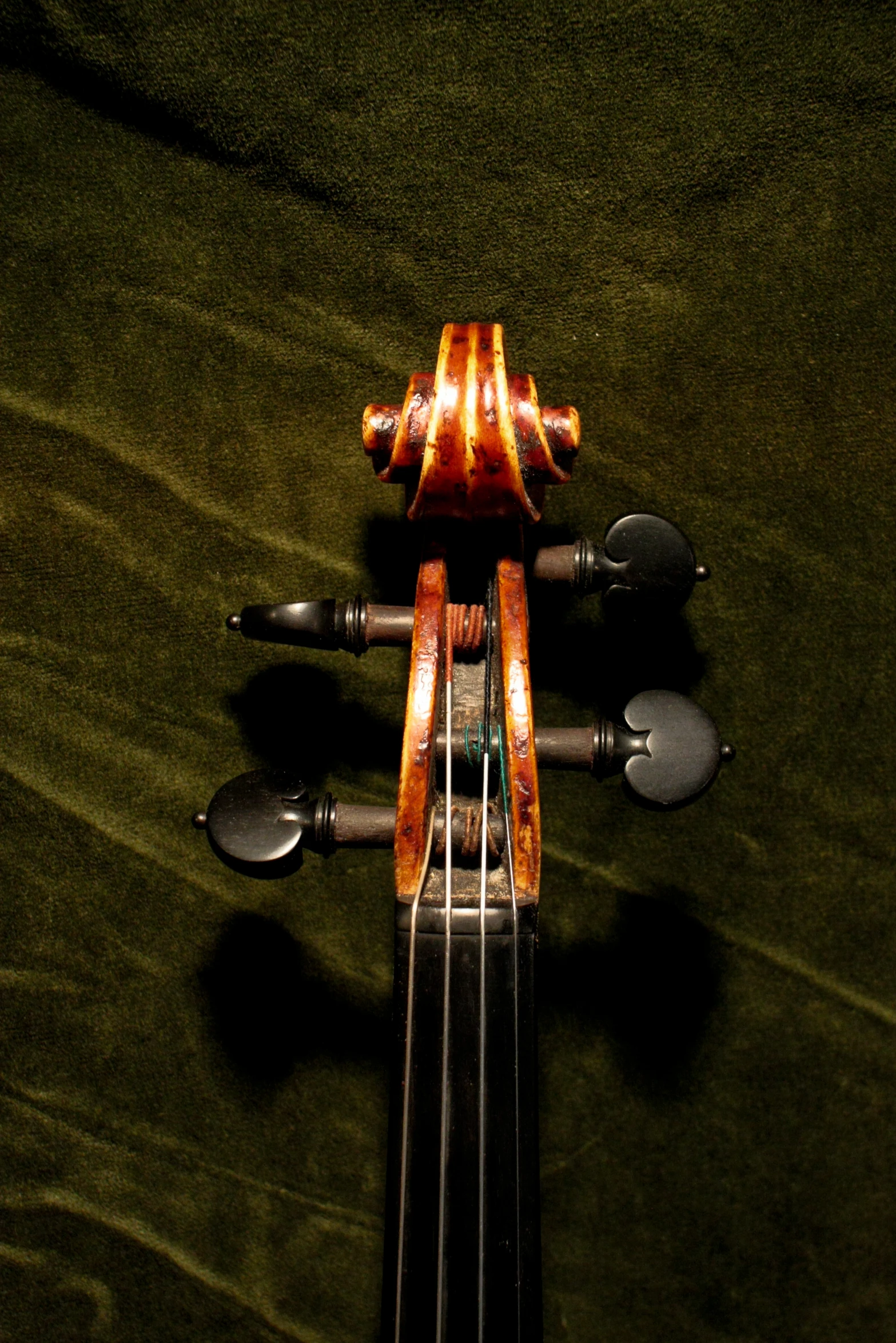 an artistic violin resting on a green velvet surface