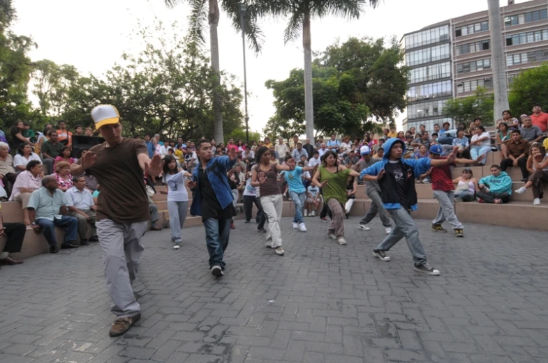 people are performing skateboard tricks on a sidewalk as the crowd looks on