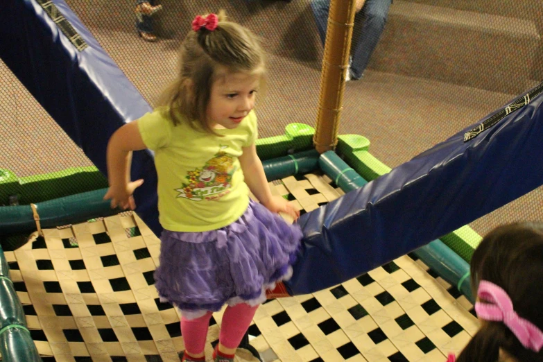 a little girl wearing some purple dress in an indoor play area