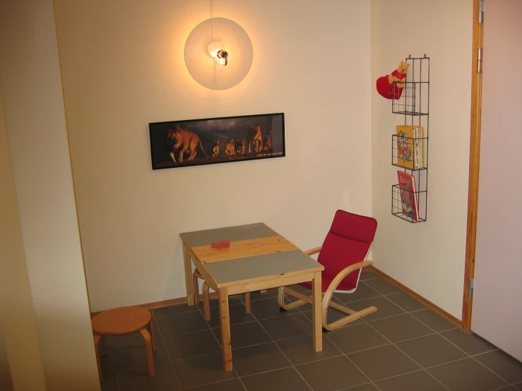 a small wooden dining table with a red chair in front of it