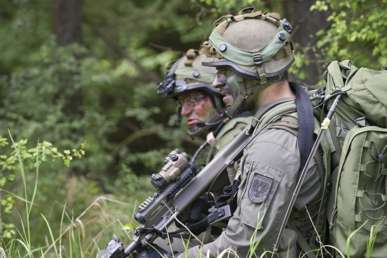 two soldiers with camouflage gear in the woods