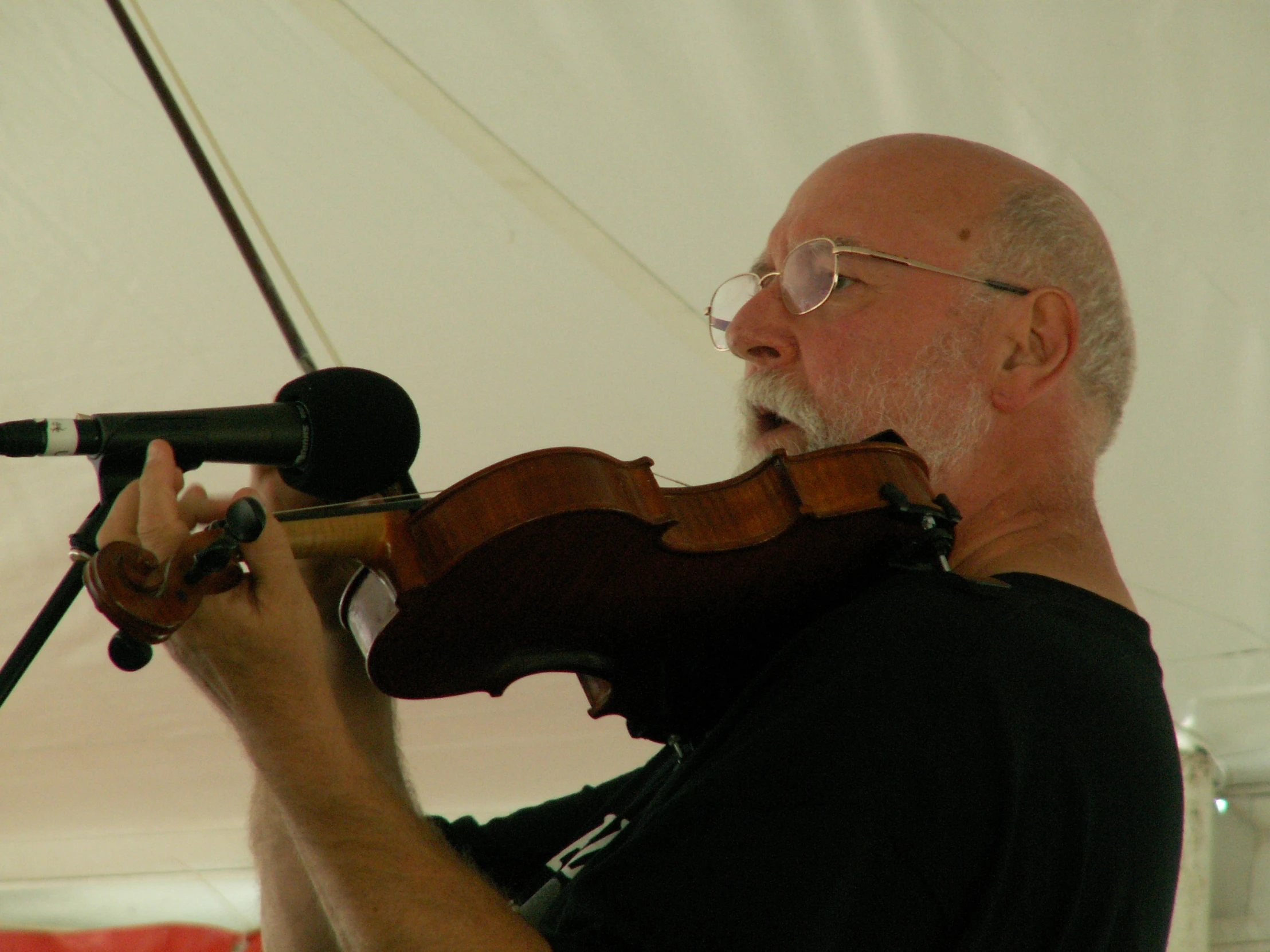 a man plays violin in a tent with a microphone