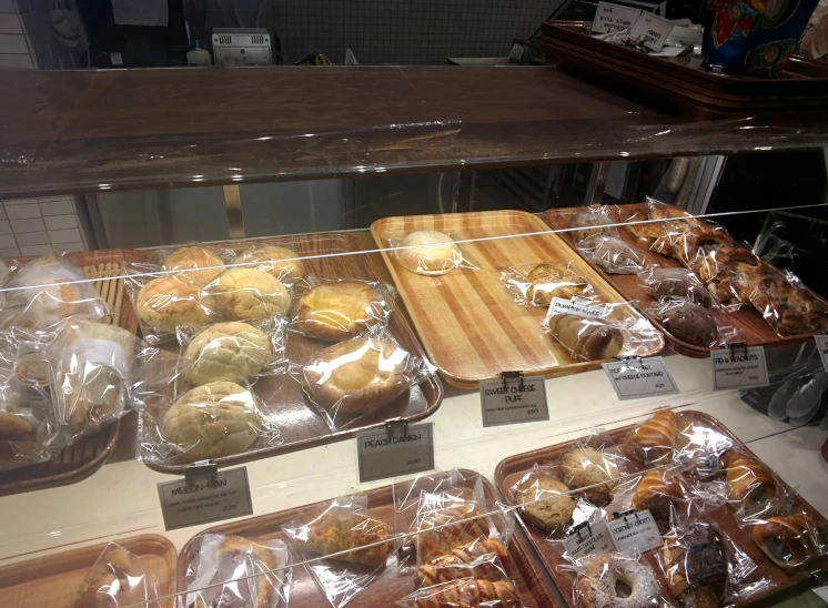 a display case filled with pastries covered in plastic