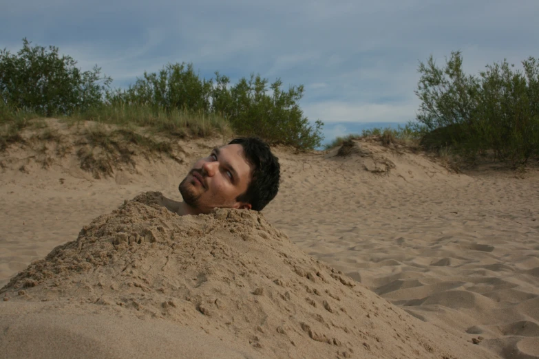 a young man lying in the sand on the beach