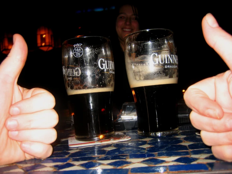 two thumbs up next to beer glasses filled with liquid