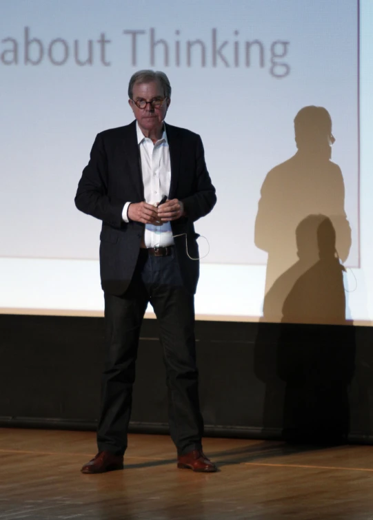 a man in a suit stands in front of a screen