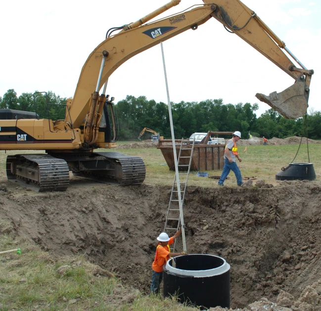 construction workers digging up the land around an excavator truck