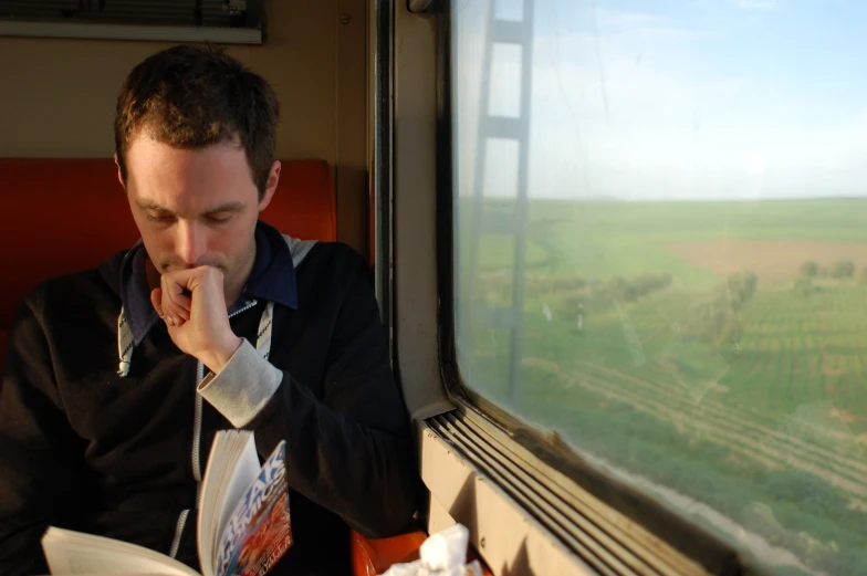 a man eats while riding a train on a cloudy day