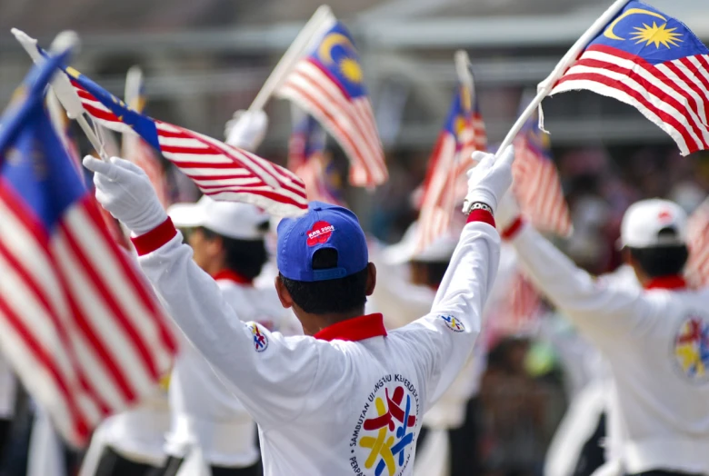 a parade of people holding american and malaysian flags