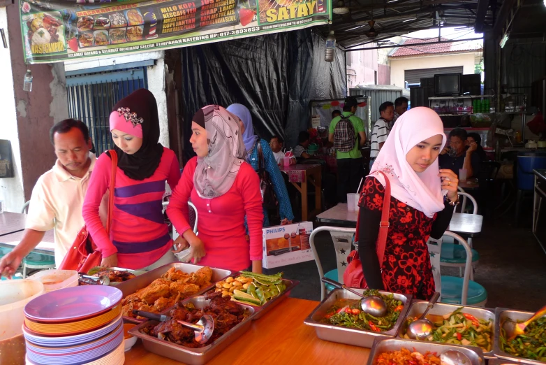 several women are standing at a table covered with food