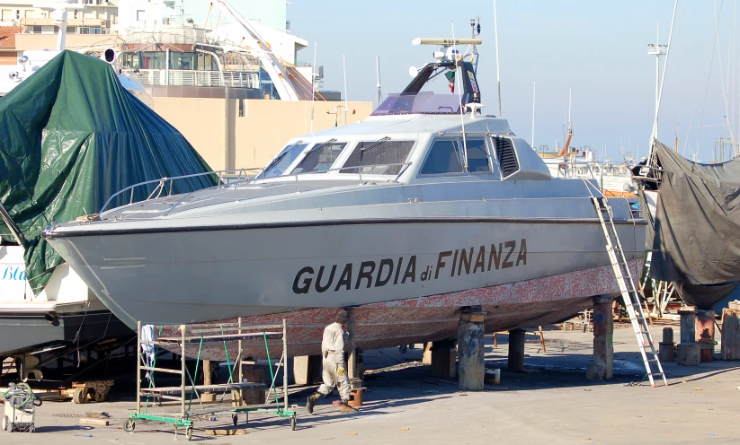 a large boat docked in a shipyard while covered by a tarp