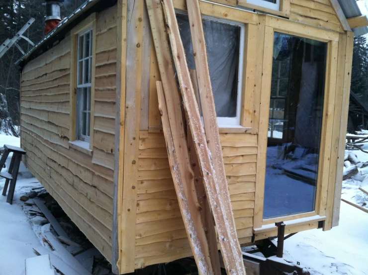 a shed with windows and a door open and a long snow broom outside
