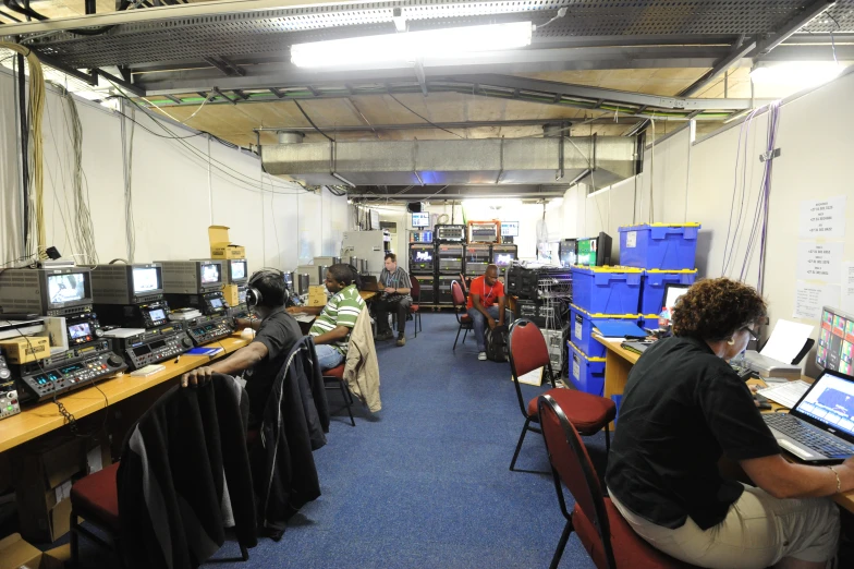 people sit in an office surrounded by computers and records