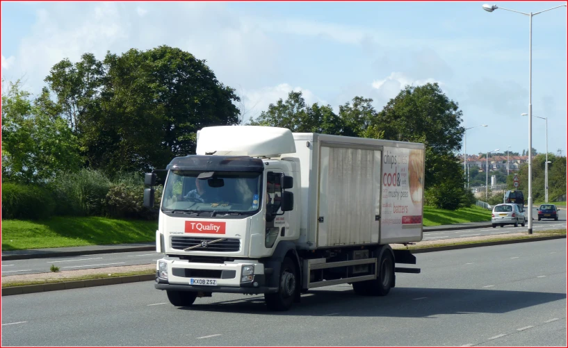 a delivery truck traveling down a road next to a forest