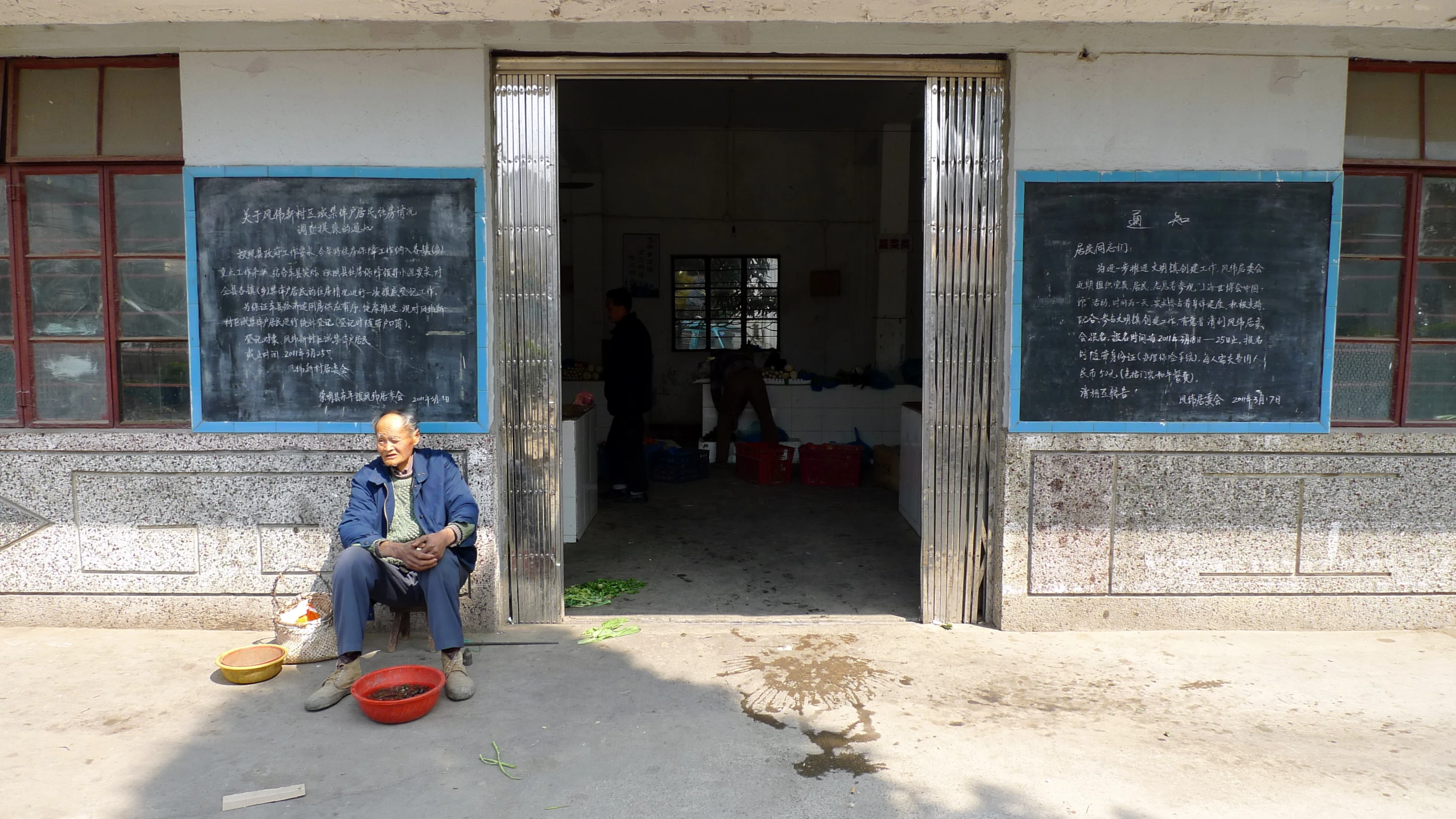 a man sits on the sidewalk in front of a chalkboard building