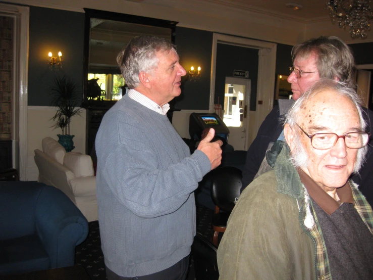 an older man is using his cellphone to talk to another older man