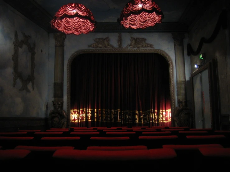 a large red curtain sitting inside of a room with red chairs