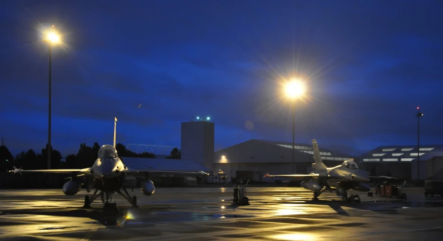 two planes parked on the tarmac at night