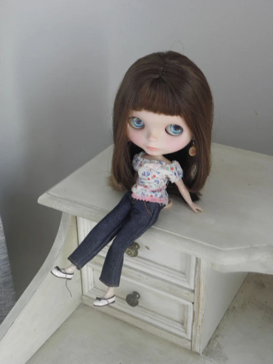doll sitting on top of a white table near drawer