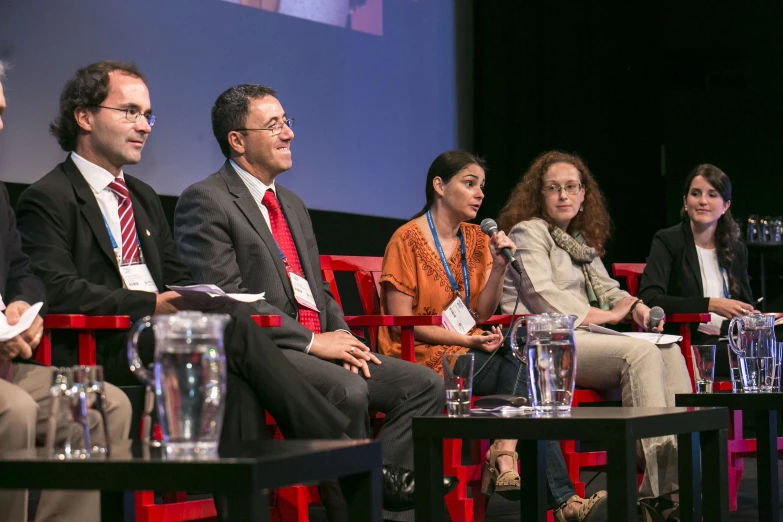 group of people seated in front of a screen at a panel