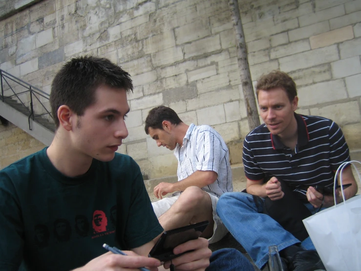 three guys sitting on the side of a building