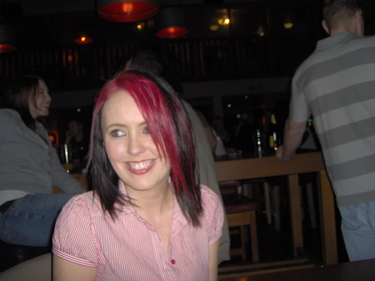 a woman with pink hair in a diner with a smile