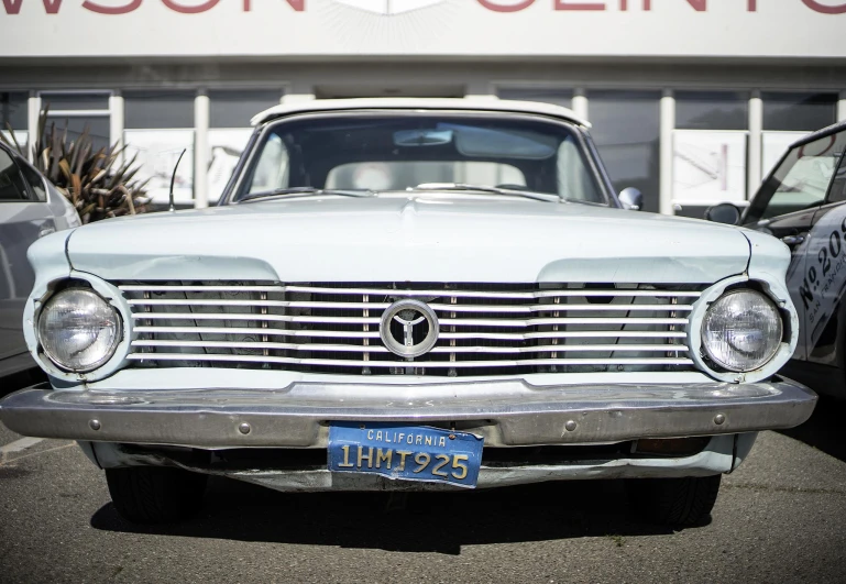 there is a old silver car with a badge on it