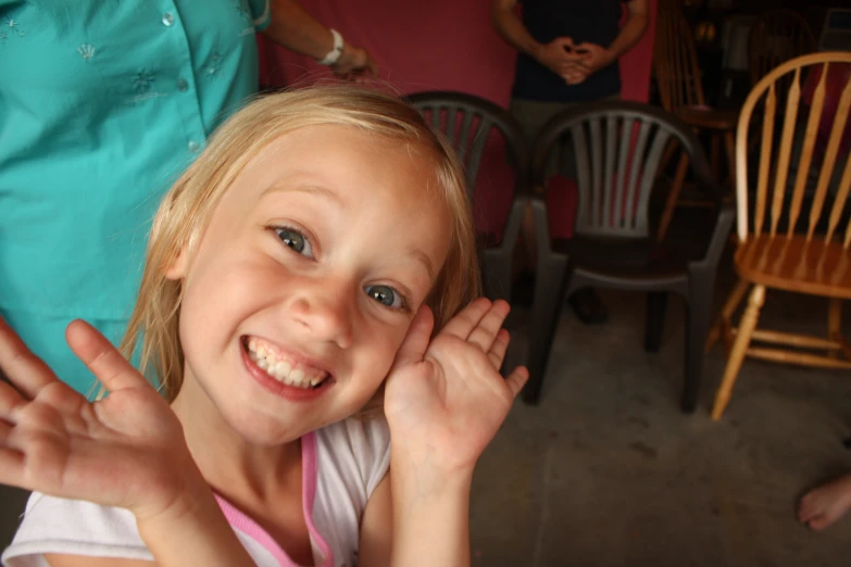 a little girl is sitting in a chair making an ugly face