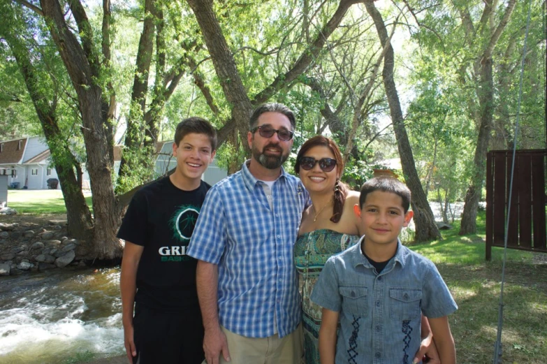 a family with two boys poses for a po near a stream