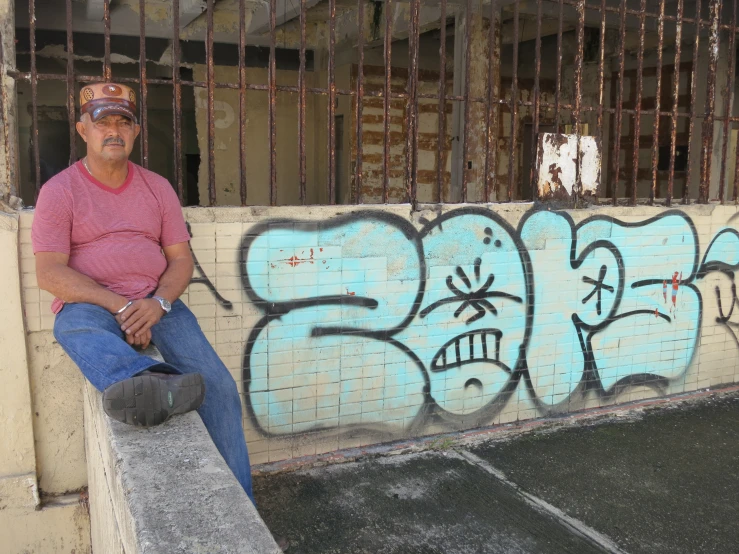 a man is sitting by a graffitied wall