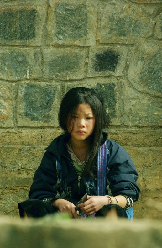 a young woman leaning on a stone wall