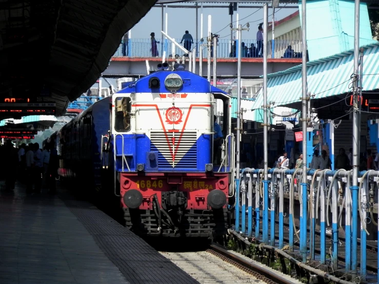 a train pulling into a station as people wait in line