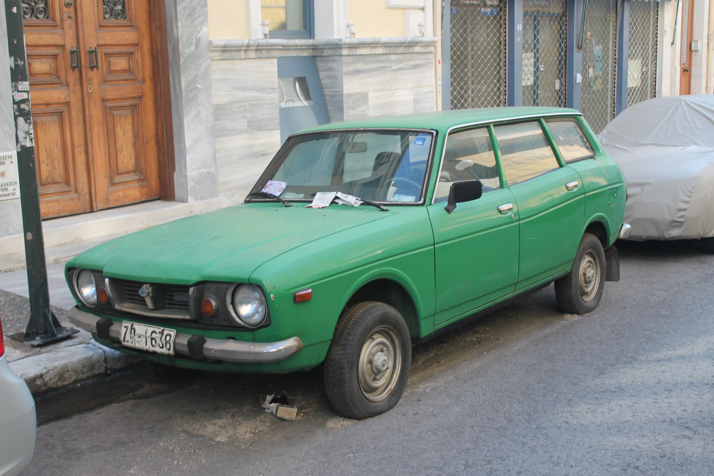 an old car parked on the street next to a fence