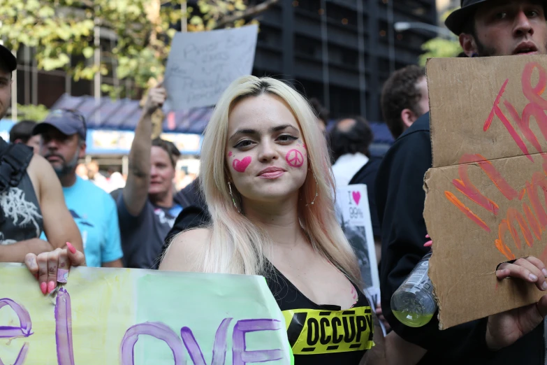 a woman with pink nose and nose paint holds placard signs