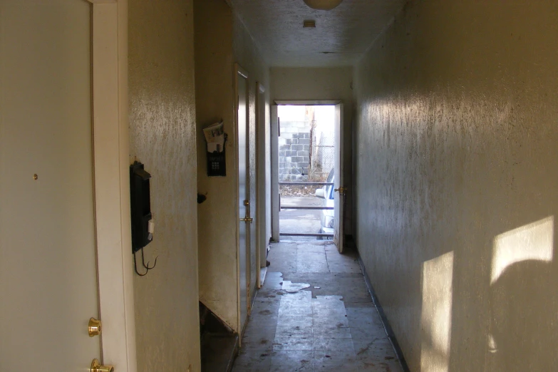 an empty narrow corridor leads to the door of an apartment building
