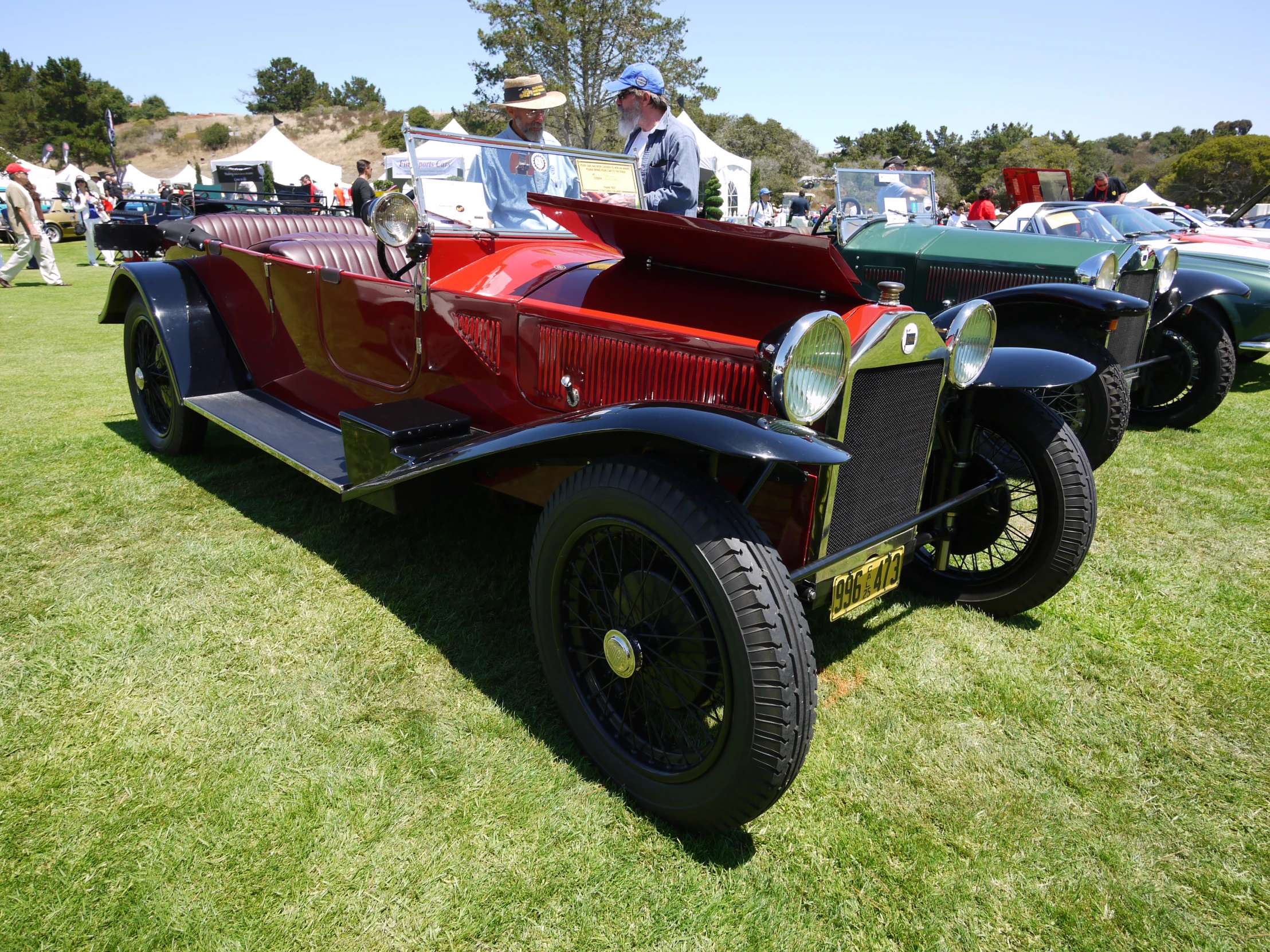 an antique car sitting on top of a grass covered field