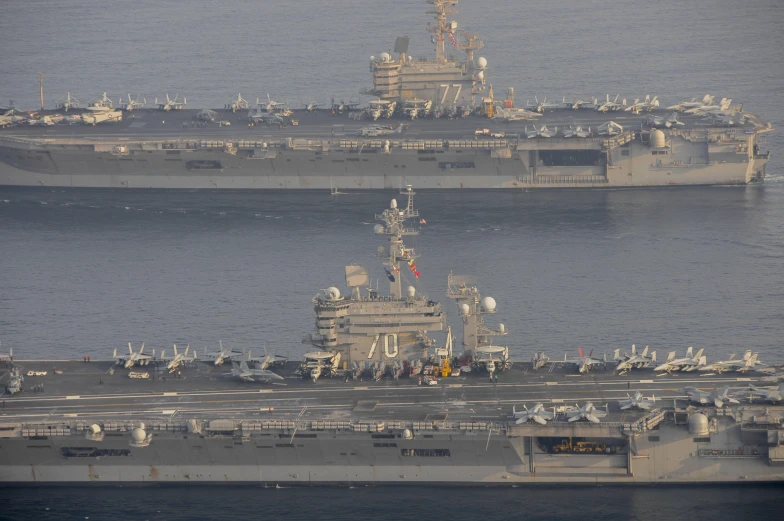 two large ships side by side with one larger in front and the other smaller behind