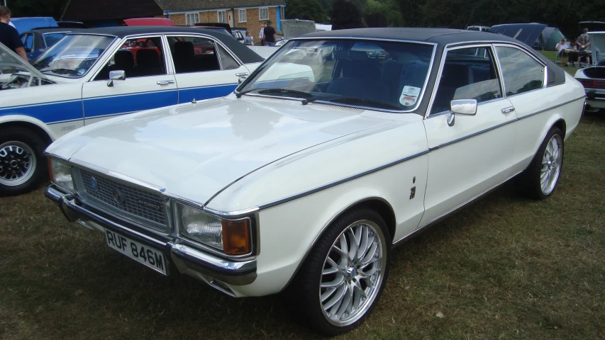 a white classic car is parked in an antique car show