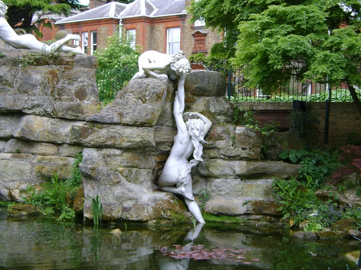 the statue is upside down in the water near a rock wall