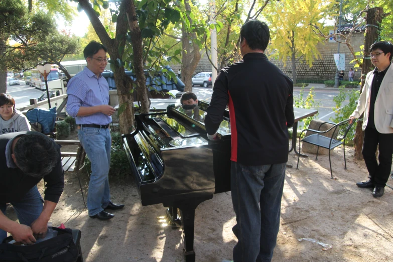 a group of men and one woman look at piano keys